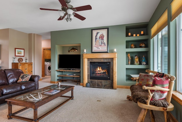carpeted living area featuring washer / dryer, built in features, ceiling fan, and a fireplace