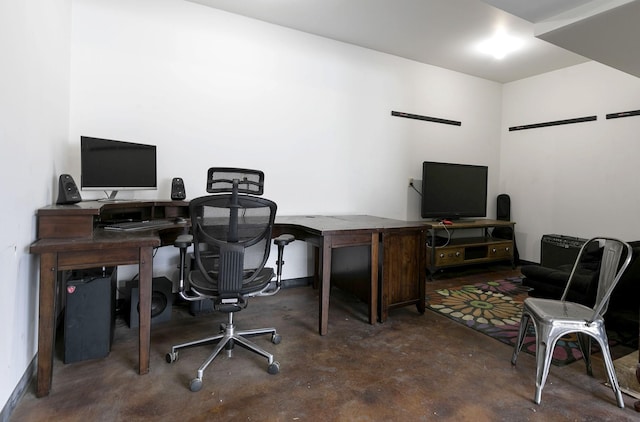 home office featuring concrete flooring and baseboards
