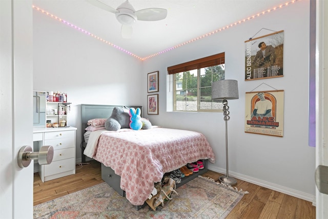 bedroom featuring a ceiling fan, baseboards, wood finished floors, and lofted ceiling