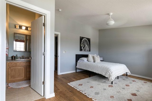 bedroom featuring light wood-type flooring, a sink, and baseboards
