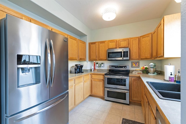 kitchen featuring light countertops, stainless steel appliances, light tile patterned floors, and a sink
