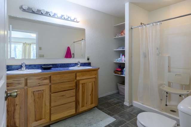 bathroom with double vanity, toilet, a shower stall, and a sink