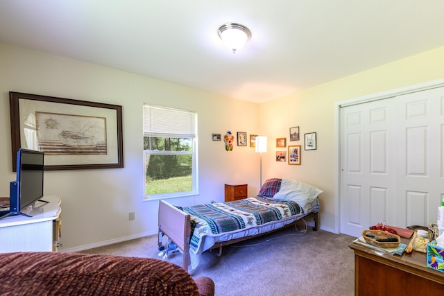 carpeted bedroom featuring baseboards and a closet