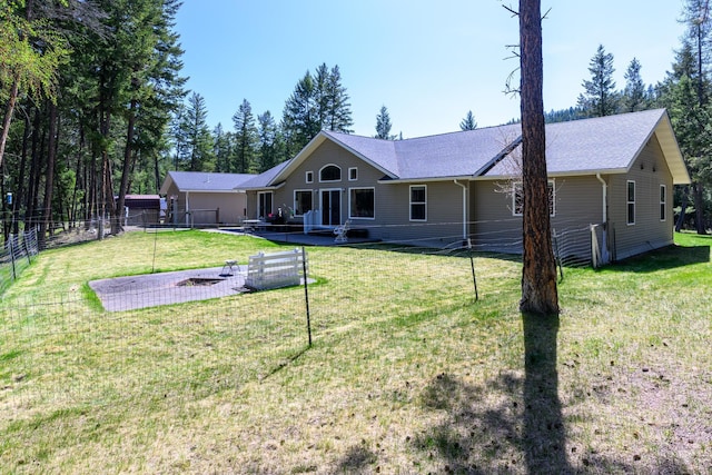 rear view of house featuring a lawn, a shingled roof, fence, and a deck