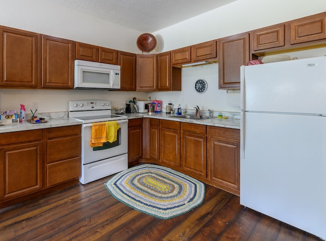 kitchen with a sink, dark wood-style floors, white appliances, and light countertops