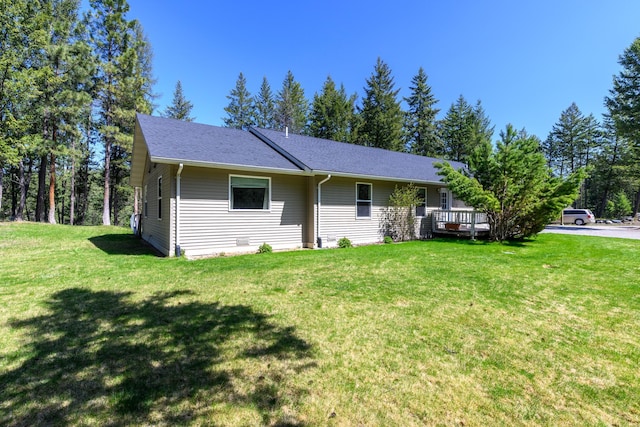 single story home featuring a wooden deck, a shingled roof, and a front yard