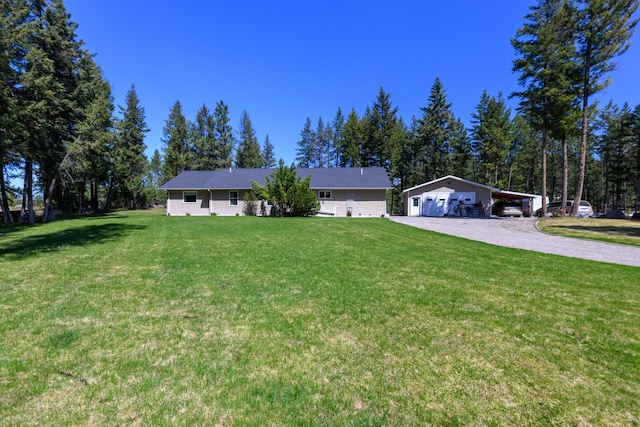 single story home featuring a detached garage, driveway, and a front lawn