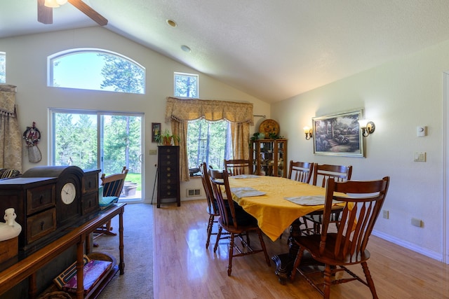 dining room with high vaulted ceiling, visible vents, a healthy amount of sunlight, and wood finished floors