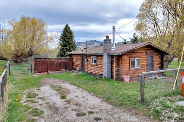 exterior space featuring a yard, fence, a chimney, and a shingled roof
