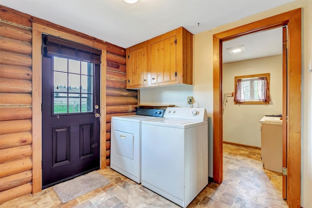 washroom with cabinet space, rustic walls, independent washer and dryer, and a healthy amount of sunlight