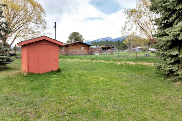view of yard with fence, an outbuilding, a mountain view, and a storage unit