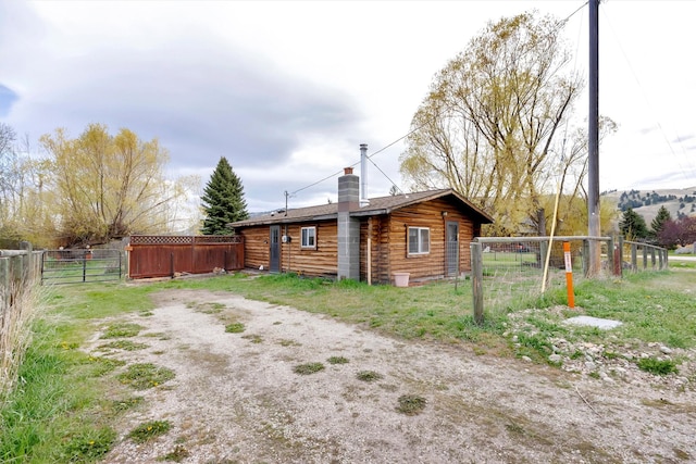 back of property featuring fence, a chimney, and a gate