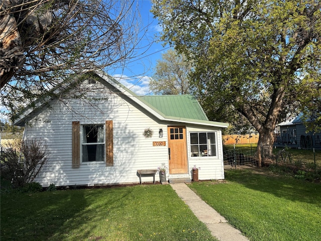 bungalow featuring fence, a front yard, and metal roof