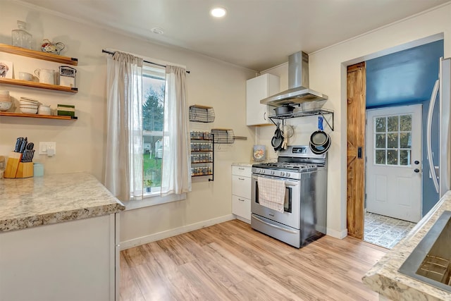 kitchen featuring appliances with stainless steel finishes, light wood-type flooring, light countertops, ventilation hood, and white cabinetry