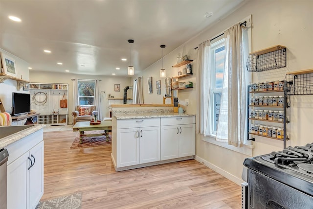 kitchen with a peninsula, gas range, recessed lighting, white cabinetry, and light wood finished floors