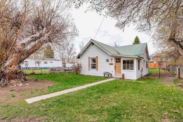 view of front of home with fence, a front yard, and metal roof