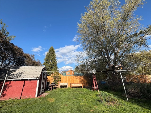 view of yard featuring a fenced backyard, a storage unit, an outbuilding, and a fire pit