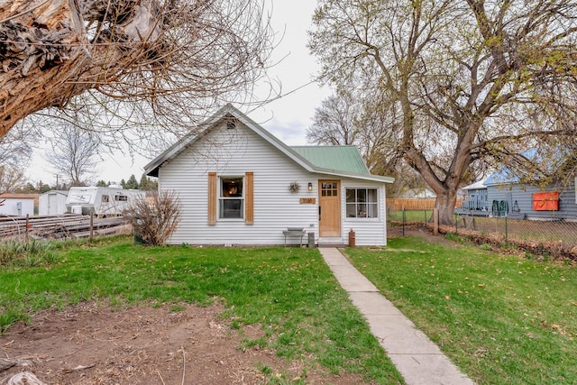 bungalow featuring fence, metal roof, and a front lawn