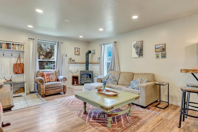 living room with recessed lighting, a wood stove, and wood finished floors