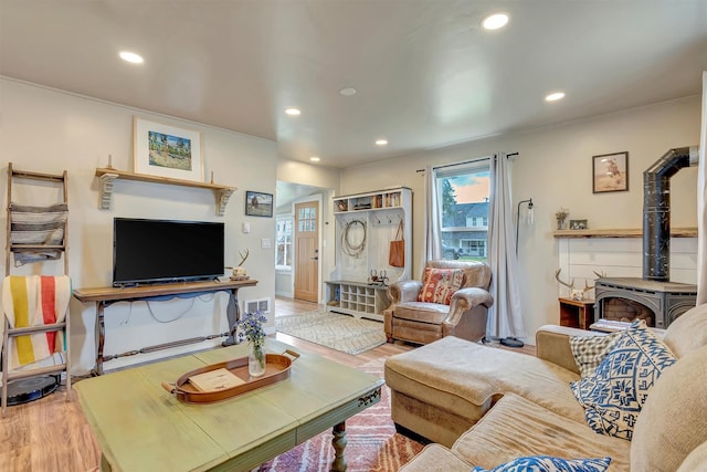 living area with recessed lighting, a wood stove, and wood finished floors