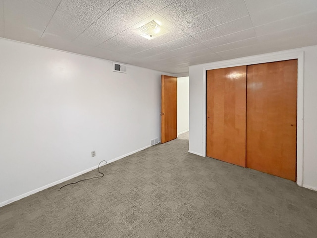 unfurnished bedroom featuring baseboards, a closet, carpet floors, and visible vents