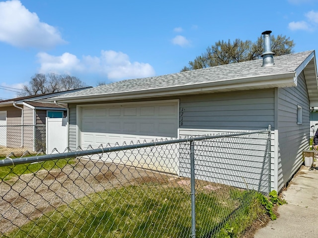 view of side of property featuring a garage, roof with shingles, and fence