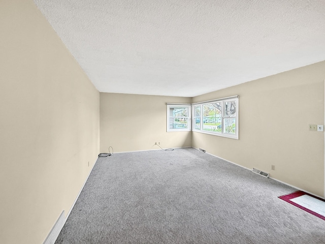 carpeted empty room with a textured ceiling and visible vents