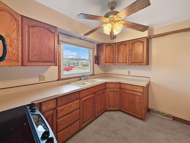 kitchen with visible vents, brown cabinets, a sink, light countertops, and light carpet