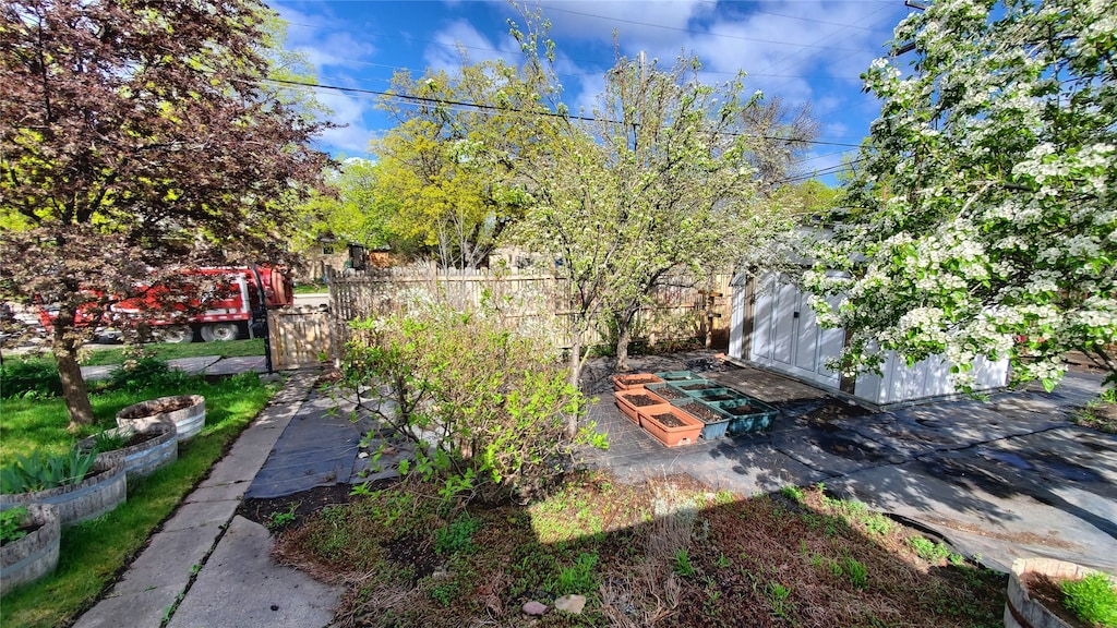 view of yard featuring an outdoor structure, a garden, fence, and a storage shed