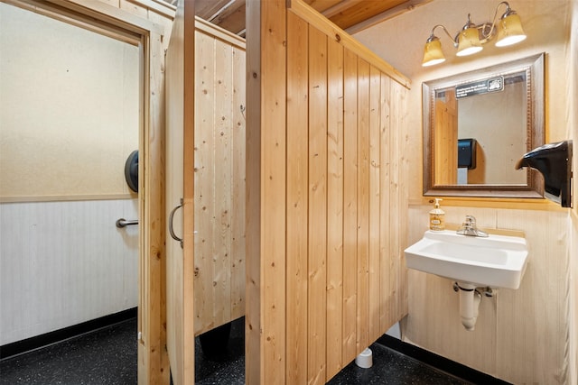 bathroom with wood walls and a sink