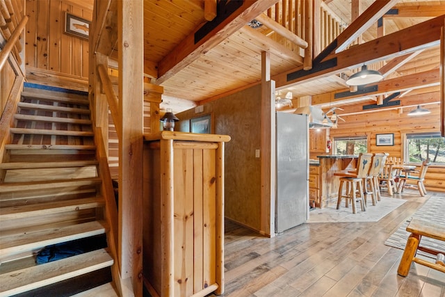 staircase featuring wooden walls, wood ceiling, beam ceiling, and hardwood / wood-style flooring
