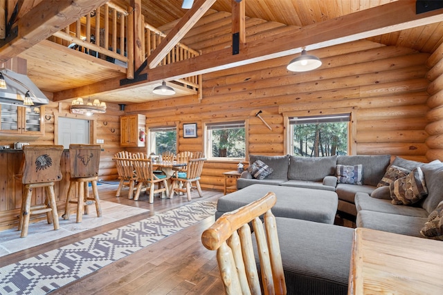 living room featuring vaulted ceiling with beams, log walls, light wood finished floors, and wooden ceiling