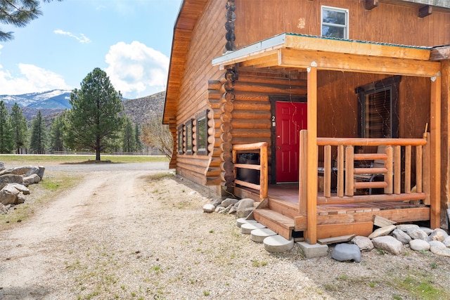 view of side of property featuring a mountain view, log exterior, and an exterior structure