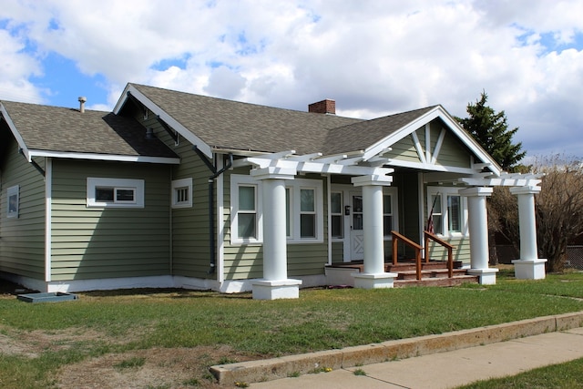 view of front of property featuring a front yard, a chimney, and roof with shingles