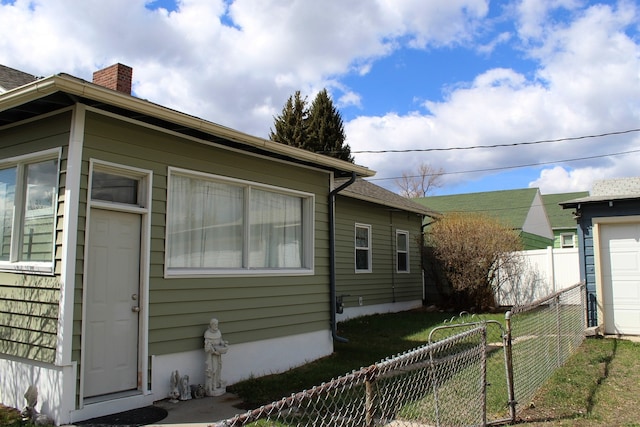 view of side of home featuring a yard, fence, and a chimney