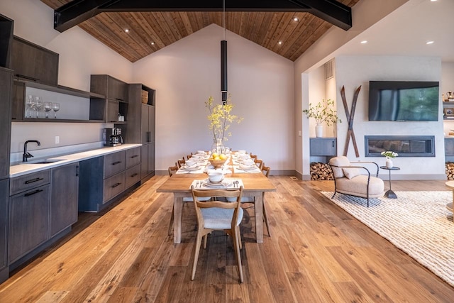 kitchen featuring open shelves, light wood-type flooring, light countertops, wooden ceiling, and a sink