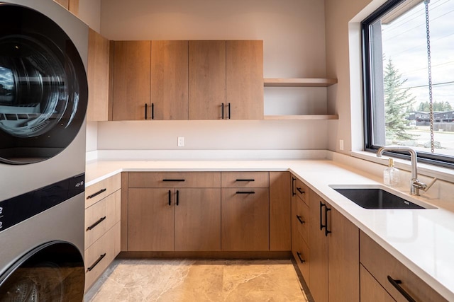 laundry area featuring cabinet space, a sink, and stacked washer / dryer
