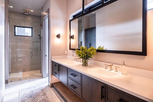 bathroom with double vanity, a sink, marble finish floor, and a stall shower