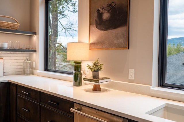 details featuring dark brown cabinets, open shelves, light countertops, decorative backsplash, and stainless steel dishwasher