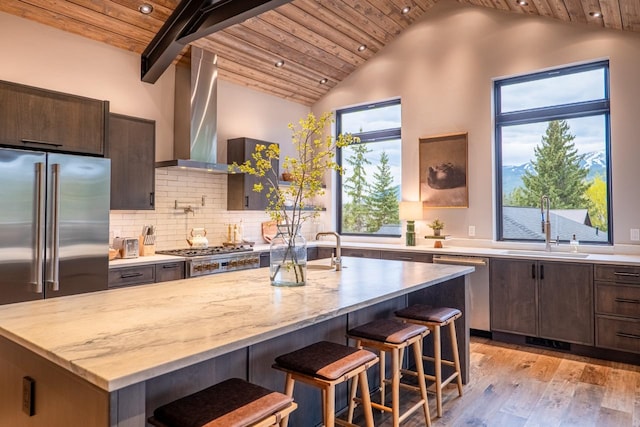 kitchen with a sink, wooden ceiling, light wood-style floors, stainless steel appliances, and wall chimney exhaust hood