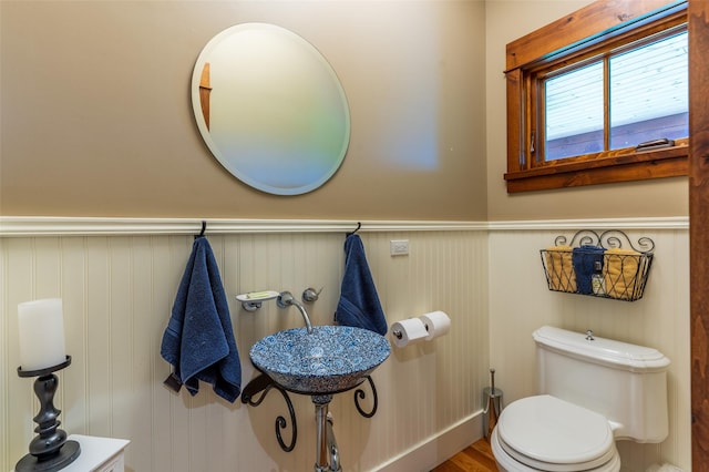 half bathroom featuring toilet and wainscoting