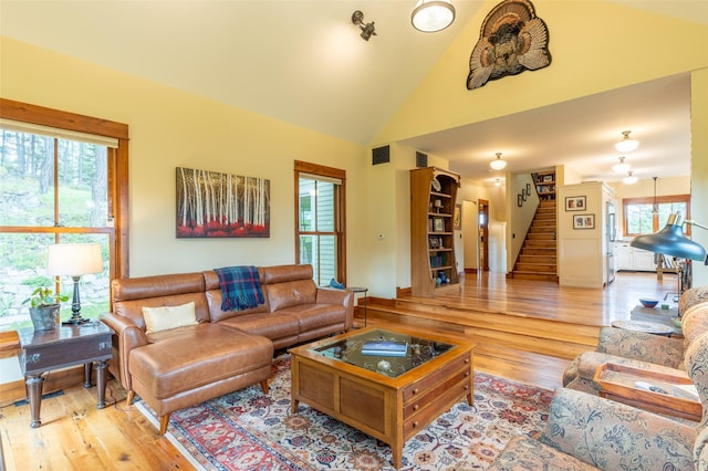 living room with visible vents, stairs, wood finished floors, and high vaulted ceiling