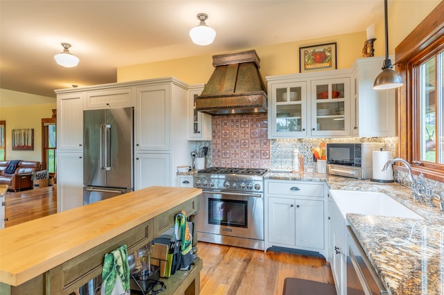 kitchen featuring custom range hood, butcher block countertops, a sink, and high quality appliances