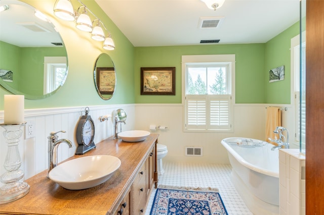 full bathroom with visible vents, wainscoting, and a sink