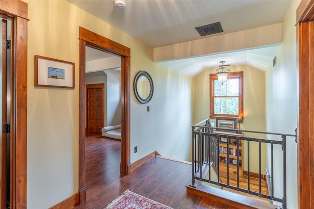 corridor with visible vents, baseboards, hardwood / wood-style floors, and an upstairs landing