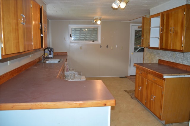 kitchen featuring baseboards, a sink, and brown cabinets