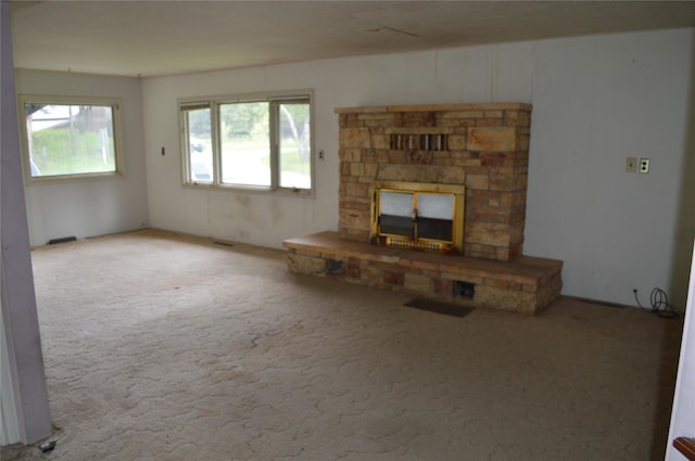 unfurnished living room with carpet floors, plenty of natural light, and a fireplace