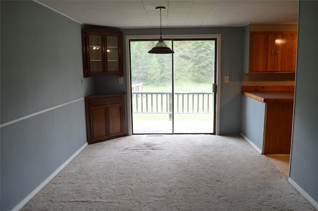 unfurnished dining area featuring light colored carpet and baseboards