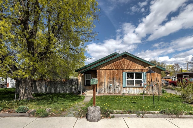 bungalow featuring a front lawn and fence