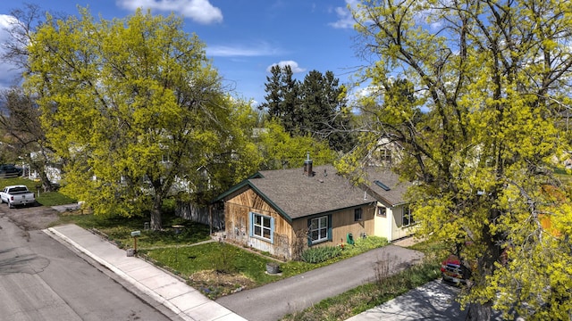 view of property exterior with a shingled roof and a yard
